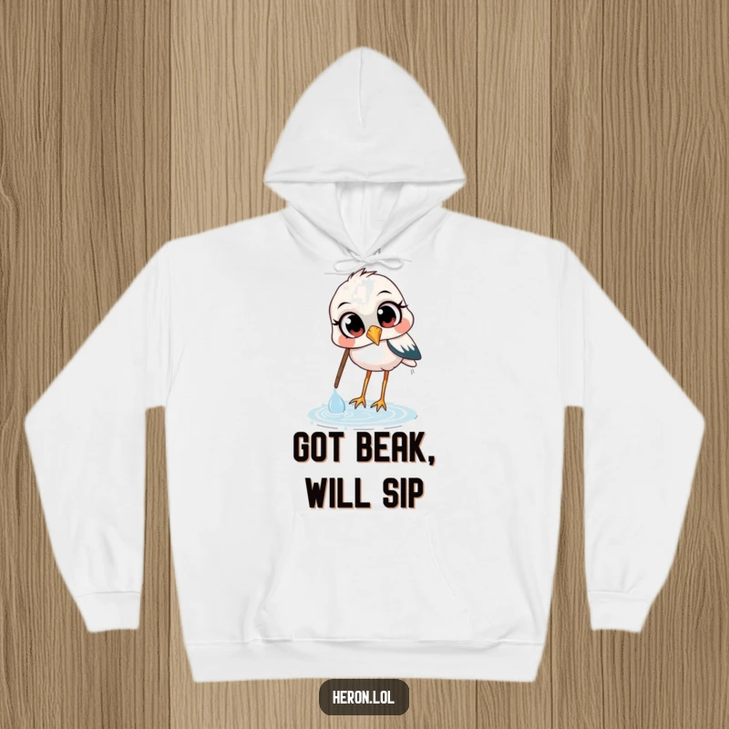 Funny hoodie showcasing a heron with wide, curious eyes, in the charming act of scooping water with its beak, a delightful and humorous scene.