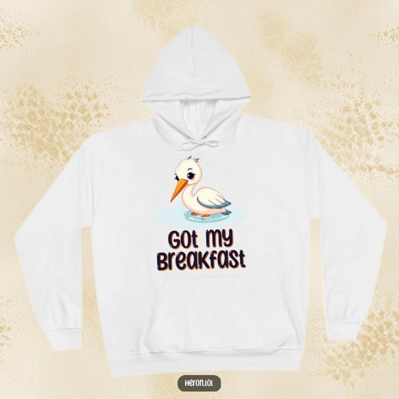 Funny hoodie showcasing a smiling heron fishing peacefully, its beak submerged in shimmering water, offering comfort and serenity.
