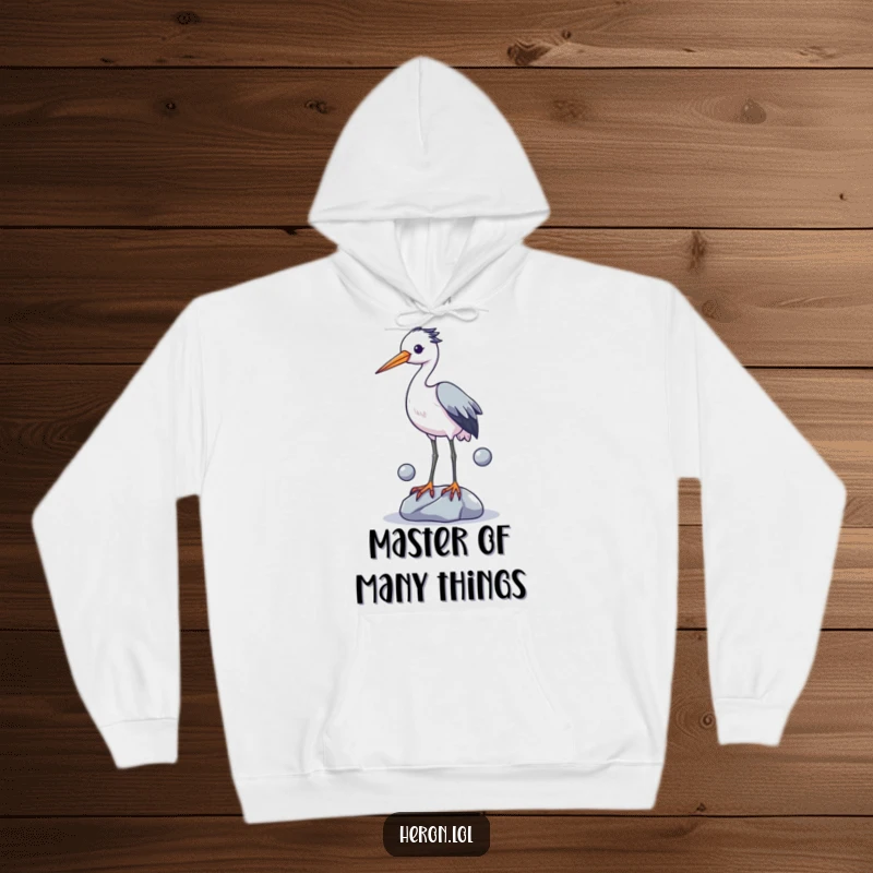 Funny hoodie showing a determined heron struggling to juggle shiny stones with its long legs, a truly comical sight for any bird lover.